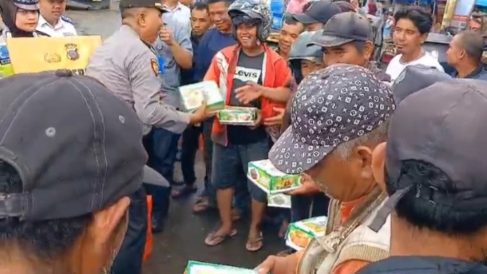 Kapolsek Padang Bolak, AKP Harun Manurung, saat berbagi nasi kotak ke pengguna Jalan yang mematuhi peraturan lalu lintas sebagai reward dalam program Jumat Berkah